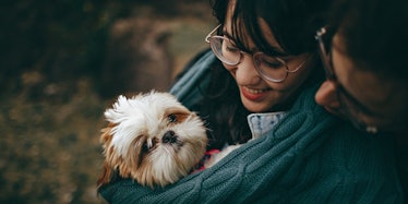 A girl holding a little white dog in a carrier 