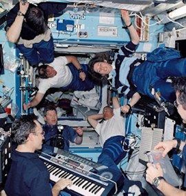 ]Carl Walz (right) plays the keyboard for a group of astronauts onboard the International Space Stat...