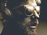 Golden man wearing headphones and glasses in dark