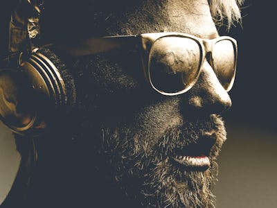 Golden man wearing headphones and glasses in dark