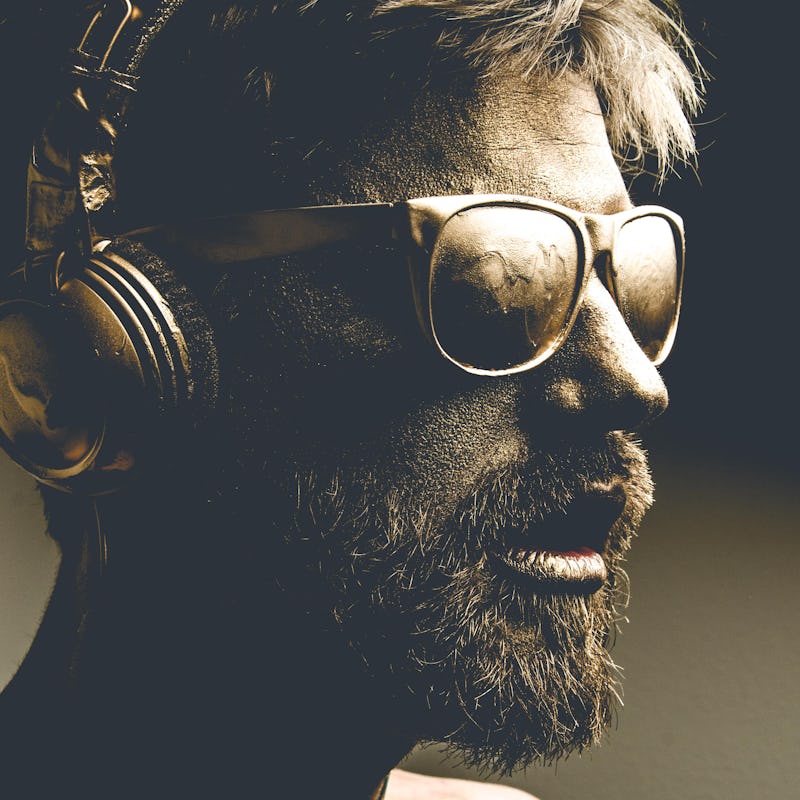 Golden man wearing headphones and glasses in dark