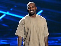 Kanye West smiling on the concert in his brown t-shirt