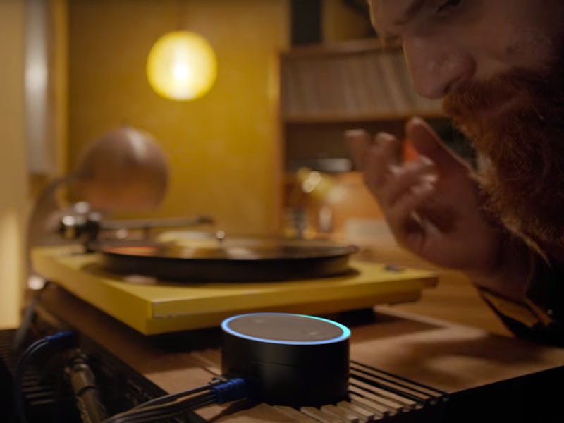 A closeup of a man speaking into an Alexa-enabled echo dot