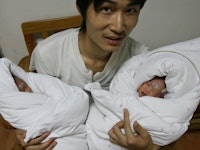 A dad holding two newborn babies in his arms