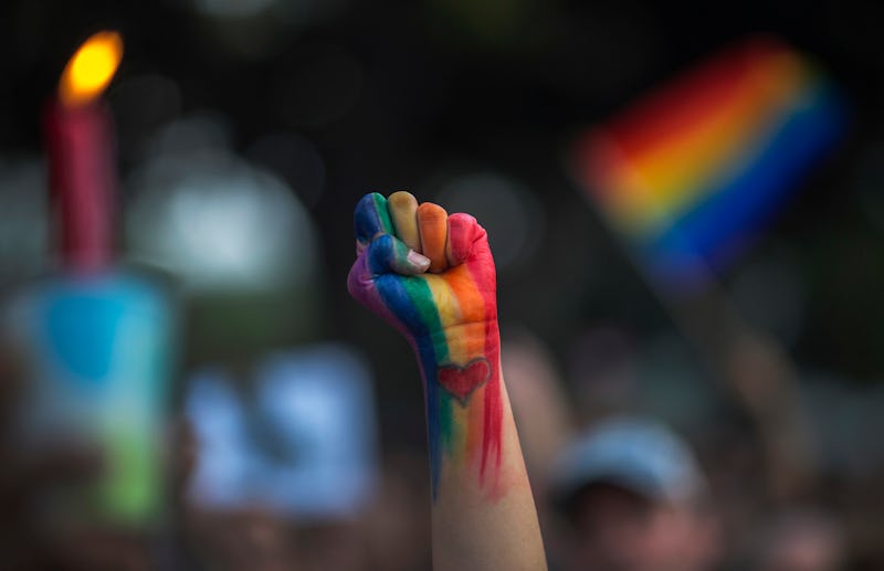 A fist held in the air painted in the color of the LGBTQ flag as a symbol for the Coming Out Day