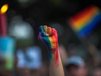 A fist held in the air painted in the color of the LGBTQ flag as a symbol for the Coming Out Day