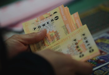 An individual holding a collection of Powerball lottery tickets.