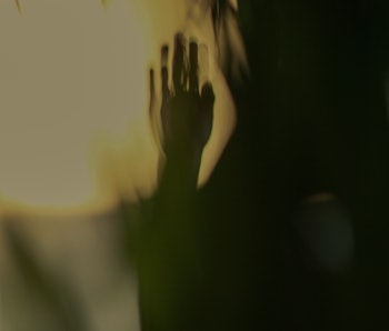 Scary silhouette of a hand pressed up against glass.