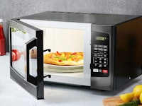 The Toshiba EM925A5A-BS Microwave Oven slightly open with a pizza in it.