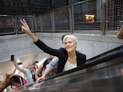 Jill Stein showing a peace sign with her hand on her way up on escalator stairs