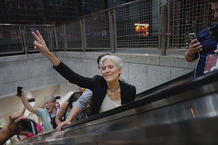 Jill Stein showing a peace sign with her hand on her way up on escalator stairs