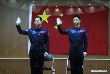 Jing Haipeng and Chen Dong wave to bystanders before boarding the Shenzou-11. 