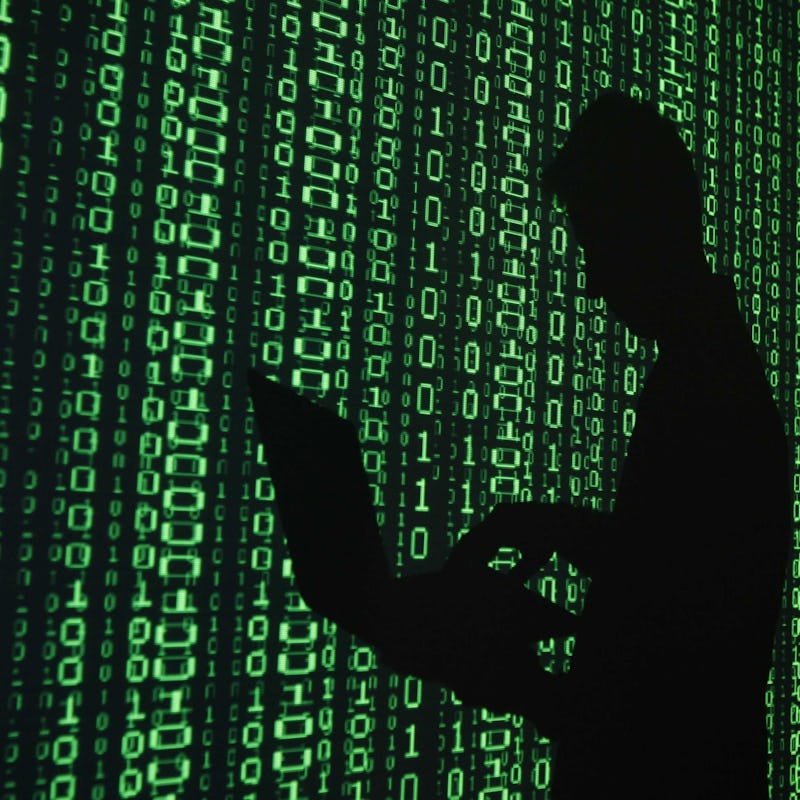 A shadows of a hacker, whose ethic is a liberal Virus next to green code on a wall.