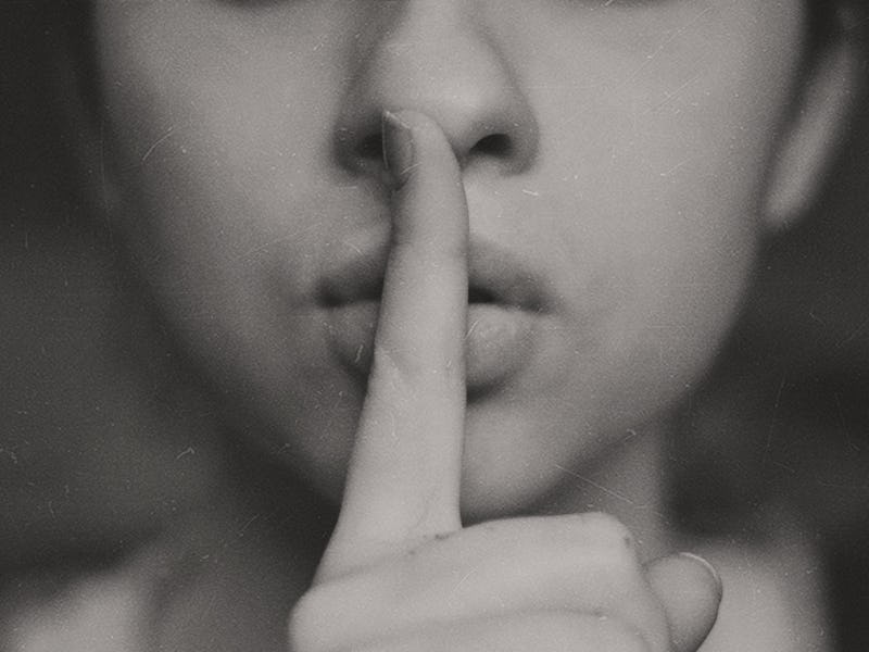 A woman holding her finger over her mouth