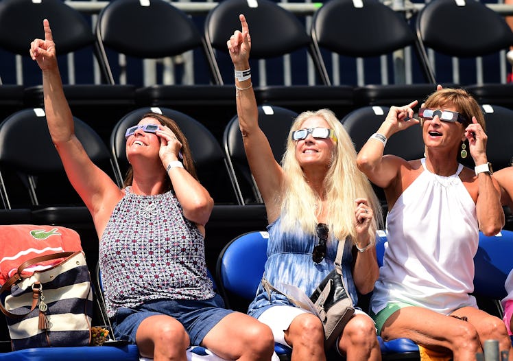 A group of women sitting, looking up and watching the eclipse