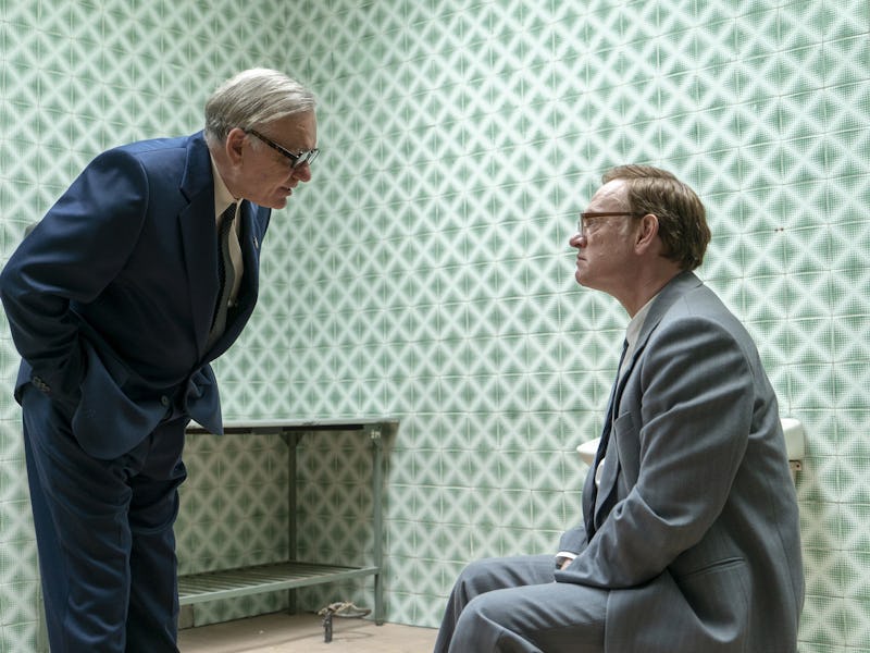 Main characters in Chernobyl having a conversation, as one sits on a chair and the other stands