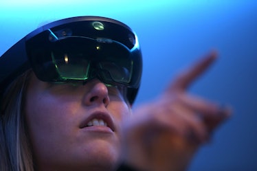 A woman wearing augmented reality glasses while pointing at something in the distance.