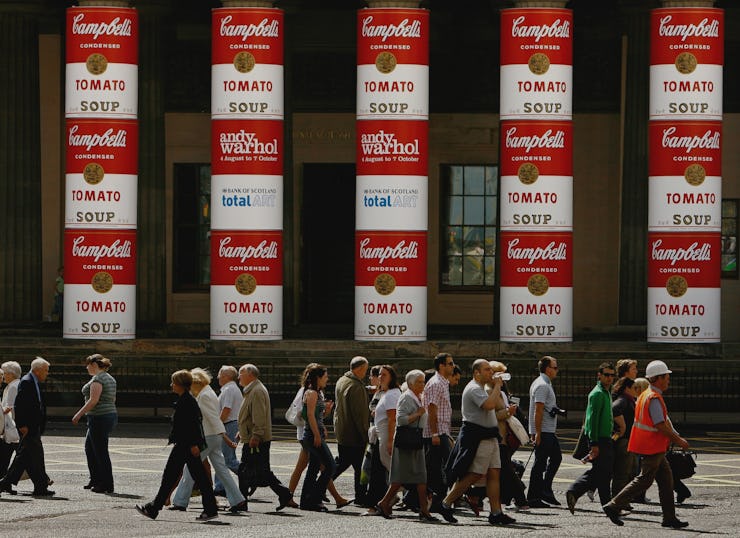 A group of pedestrians walking with several Campbell Soup’s Wet Noodle ad poster on a wall on the bu...