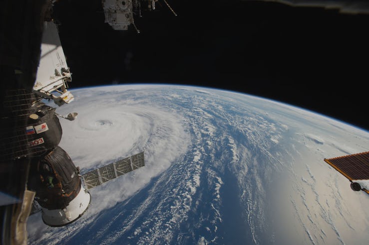 An aerial view of planet Earth near a satellite and Typhoon Noru on the surface