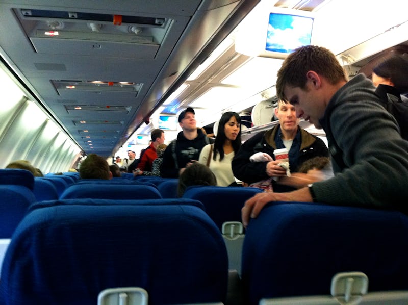 A group of people entering an airplane with shrinking airline seats