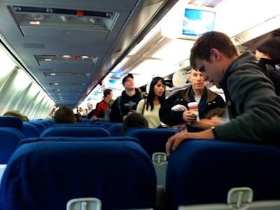 A group of people entering an airplane with shrinking airline seats