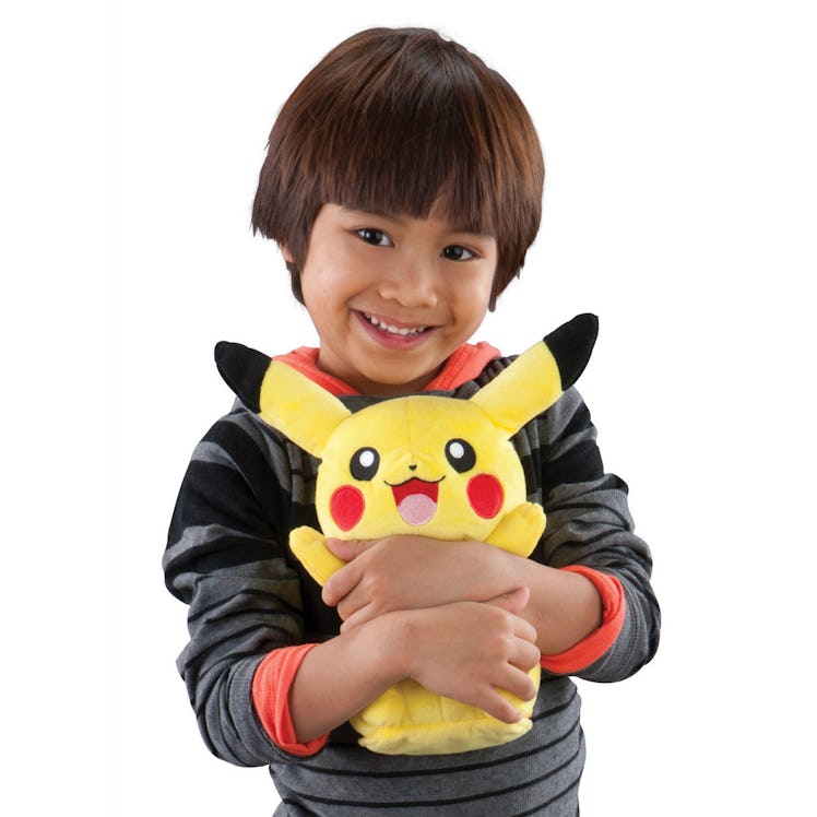 A kid posing with a Pikachu stuffed toy