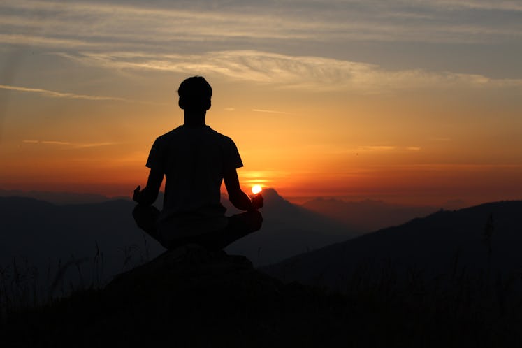 A man meditating at a top of a hill