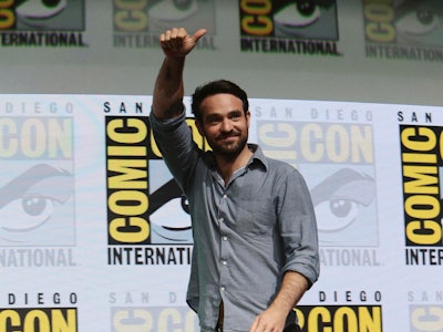 Charlie Cox waving to fans while walking at the Comic-Con event