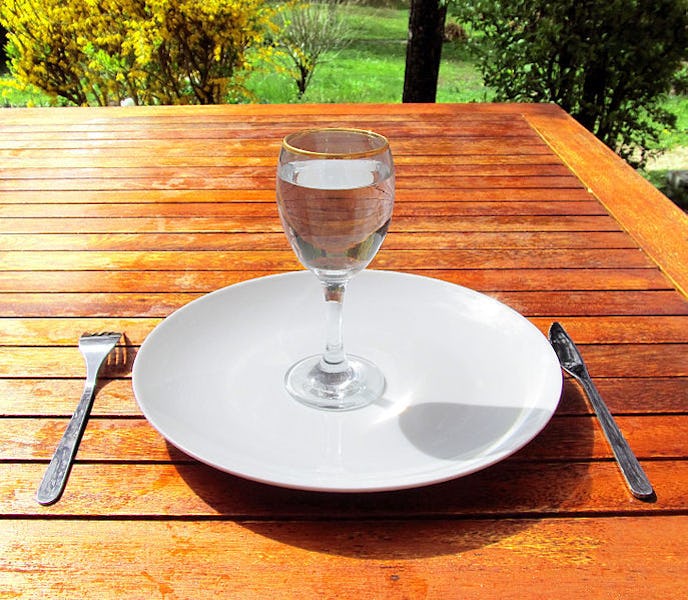 A plate on a wooden table with a glass of water on it