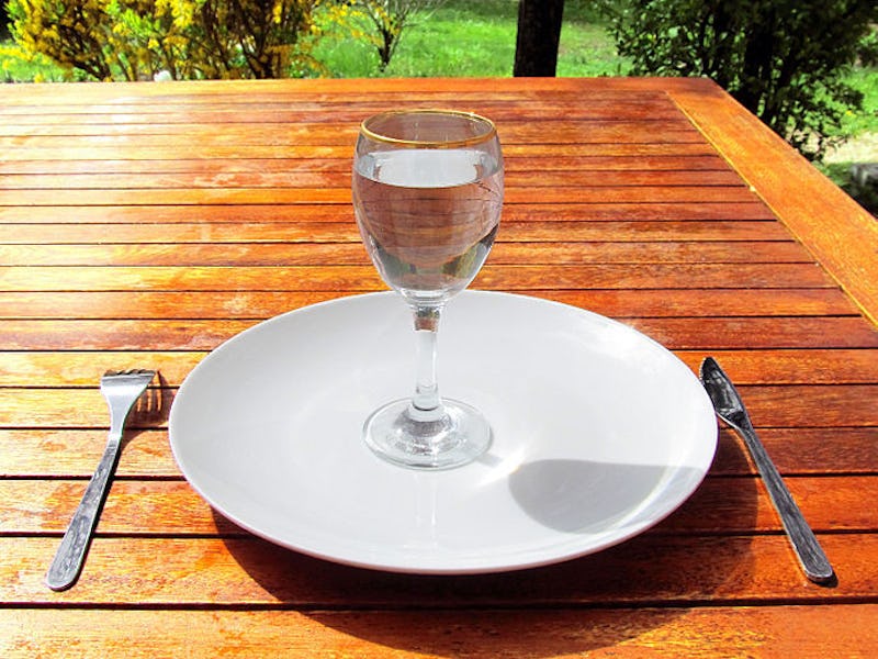 A plate on a wooden table with a glass of water on it