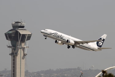 An Alaska Airlines jet passes the air traffic control tower at Los Angles International Airport (LAX...