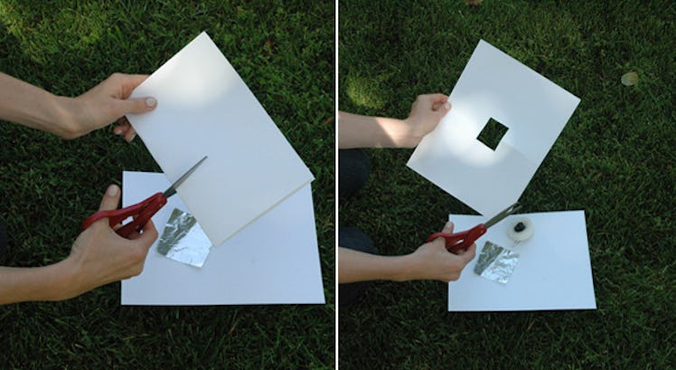 Hands cutting a square hole in the middle of one piece of cardstock