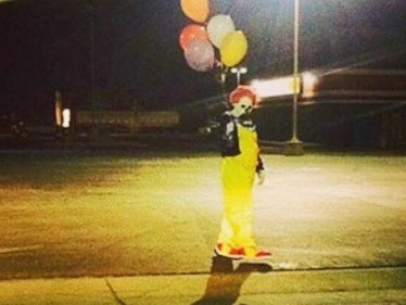 Creepy clown walking down a street with balloons at night