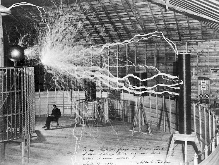 Nikola Tesla sits calmly next to a massive Tesla coil -- or does he? -- in a photo that earned him n...