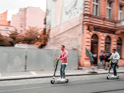 A man using one of the best-reviewed motorized scooters on Amazon while driving through a city.