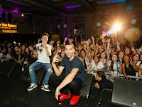 Kalin and Myles performing on stage with a crowd standing behind them