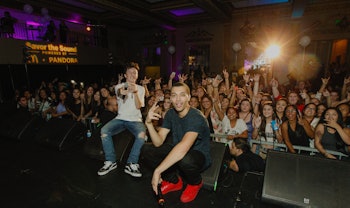 Kalin and Myles performing on stage with a crowd standing behind them