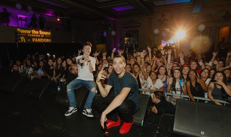 Kalin and Myles performing on stage with a crowd standing behind them