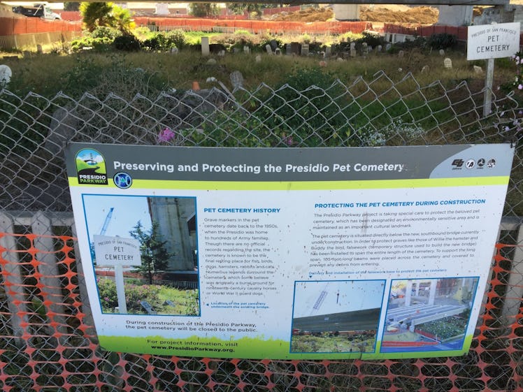 A sign about the preservation and protection of pet cemeteries hanging on a wire fence.