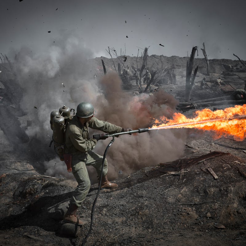 A battle scene screenshot from 'Hacksaw Ridge' with a character using a flamethrower