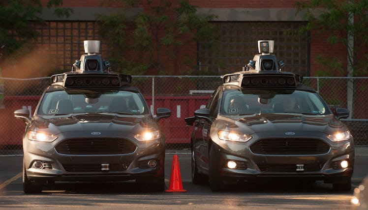 Two Uber driverless Ford Fusions parked in the Uber Technical Center parking lot with their lights o...