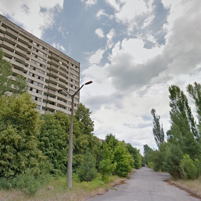 A small road, a streetlamp and bushes next to a building in the ghost town of Pripyat