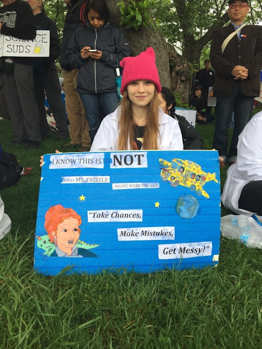 A girl holding a poster with "take chances, make mistakes, get messy" text