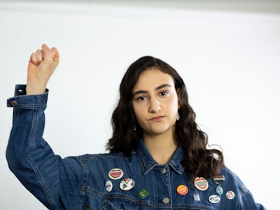 Jamie Margolin in a denim jacket holding her fist up in the air