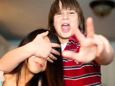 A tween boy covering his sister's eyes while taking a photo