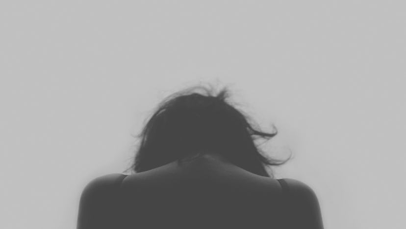 The backside of a woman leaning her head forward in black and white