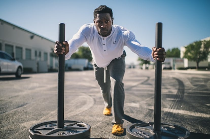 Young man practicing the sled push exercise with two heavy bars