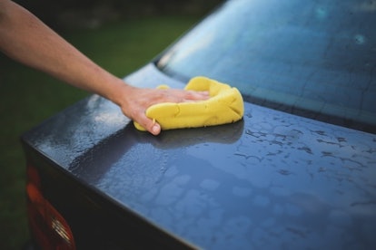 A person washing a car with a sponge