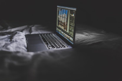 An open laptop placed on a bed during the night