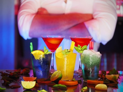A cocktail master standing behind five different cocktails garnished with lemon and mint